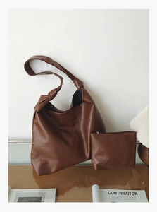 Detail of dark brown leather hobo bag with knotted strap and matching small zipper pouch