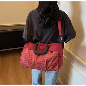 Back view of a burgundy travel bag with plaid patterns worn by a model in casual setting