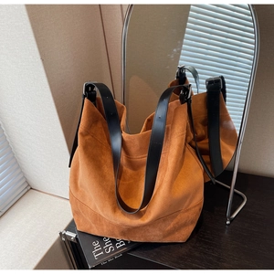 Detail of caramel suede tote bag featuring adjustable black wide leather strap and silver buckle
