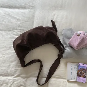 Detailed view of dark brown suede crescent bag with knot detail on the shoulder strap