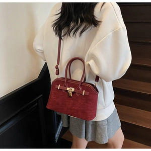 Détail d'un sac bandoulière bordeaux en forme de coquille avec fermoir en métal doré