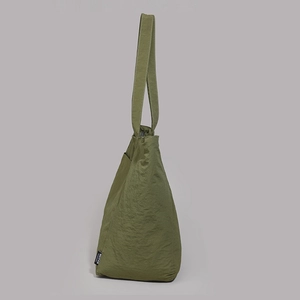 Détail du sac à épaule en nylon vert olive avec texture gaufrée et étiquette de marque