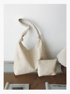 Detailed macro view of cream leather tote bag material with chic knot strap detail