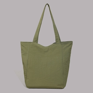 Détail du sac fourre-tout en nylon vert armée avec bandoulière et texture plissée