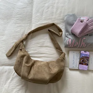 Detailed texture of brown suede hobo bag featuring decorative knot and crescent shape