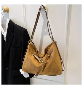 Detailed macro view of brown suede tote bag featuring brown leather straps and gold metal hooks
