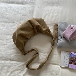 Detail view of a brown suede croissant bag featuring a unique knotted shoulder strap