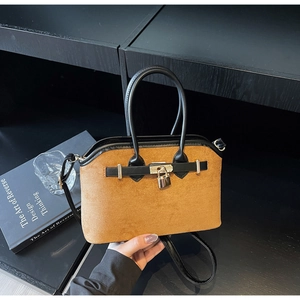 Détail du sac en daim marron avec poignées en cuir noir et fermoir cadenas doré