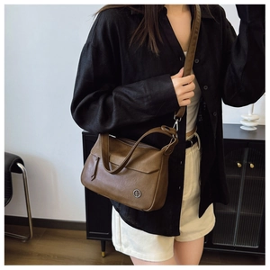 Detailed view of vintage brown leather handbag with metal logo and fine stitching