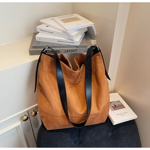 Close-up of brown suede tote bag featuring black leather strap and silver metal buckle