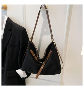 Detail of black canvas hobo bag with brown leather strap and gold metal hardware