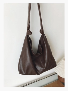 Detail of a dark brown hobo bag featuring a stylish knotted shoulder strap and soft PU leather