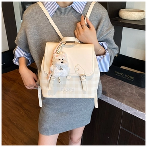 Close-up of cream checkerboard backpack featuring IBOME embroidery and plush dog charm
