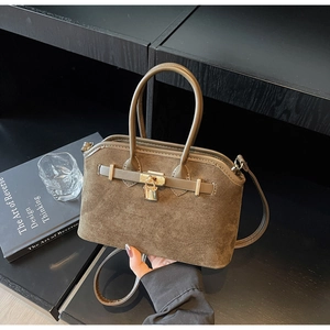 Détail d'un sac à main en daim marron avec cadenas doré et design élégant