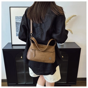 Rear view of vintage brown leather crossbody bag with metal logo and dual shoulder straps