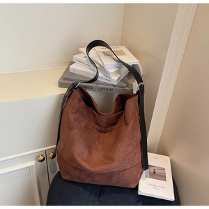 Detail of dark brown suede hobo bag with adjustable black leather shoulder strap