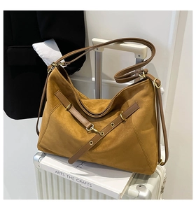 Detail of caramel suede tote bag featuring gold metal rings and premium leather straps