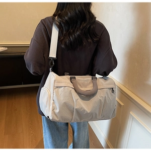 Detailed view of grey checkered duffel bag with NINGJIA embroidery and side compartment