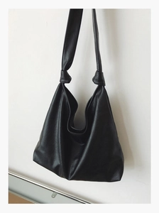 Close-up of black faux leather Hobo bag featuring a unique knotted shoulder strap detail