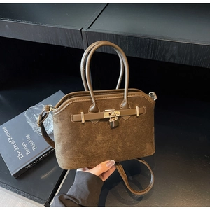 Vue détaillée du sac coquille en daim marron avec cadenas doré et poignées en cuir
