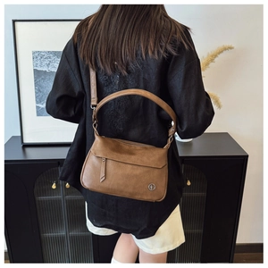 Detailed view of brown vintage leather shoulder bag with adjustable strap and metal logo