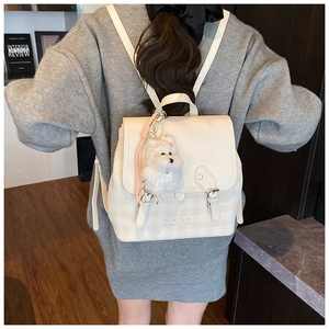 Detail view of beige backpack with grey checkered pattern and plush puppy charm