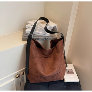 Detail of soft brown suede tote bag featuring black leather strap and silver metal buckle