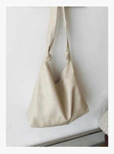 Detail view of the beige hobo bag showing the unique knotted shoulder strap and soft leather texture