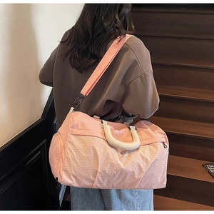 Close-up of pink quilted sports bag featuring woven handles and a detachable shoulder strap