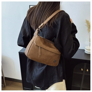 Close-up of vintage brown leather underarm bag with silver logo and matte texture