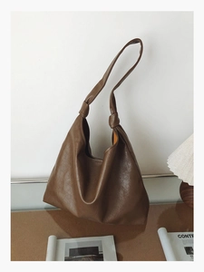 Detailed view of dark brown tote bag featuring unique knotted strap and wrinkled leather