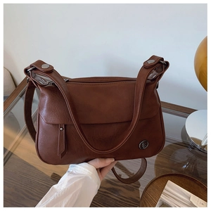 Detail of vintage brown leather handbag featuring dual straps and fringe charm