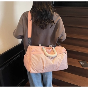 Pink waterproof travel bag with woven base texture and double handles shown on stairs