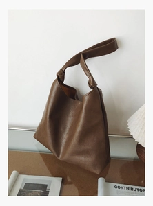 Detailed close-up of large brown tote bag with textured faux leather and knotted strap