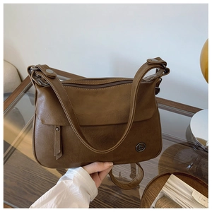 Detailed macro view of vintage brown crossbody bag texture with metal logo and fringe