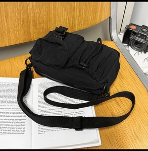 Detailed macro view of black tactical nylon crossbody bag with buckle and drawstring pockets