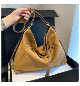 Close-up of brown suede tote bag with smooth leather straps and gold buckle details