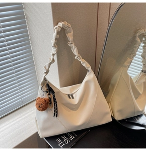 Détail du sac cabas blanc cassé en cuir grainé avec bandoulière plissée et porte-clés ours