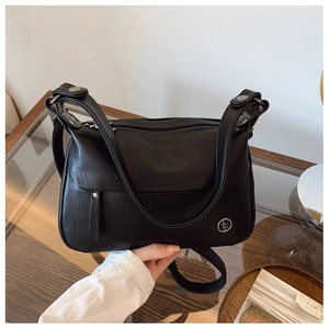 Detail view of black vintage square bag with multiple zippers and round metal logo