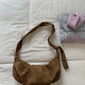 Detail of brown suede hobo bag featuring wide strap with knot detail and large capacity