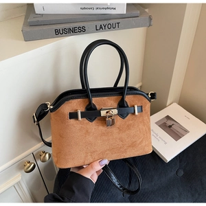 Détail de la texture mate brune avec garnitures en cuir noir et cadenas doré du sac