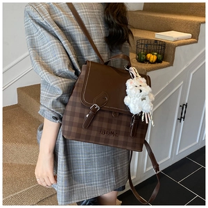 Detail view of brown checkerboard backpack with premium leather straps and plush dog charm