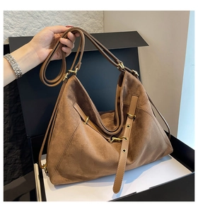 Detailed macro view of large brown suede tote bag with golden hardware and leather strap