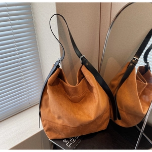 Detail of caramel suede tote bag with adjustable black leather strap and metal hardware