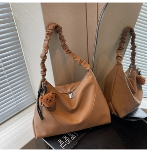 Détail du sac hobo en cuir camel avec bandoulière froncée et breloque ours mignon