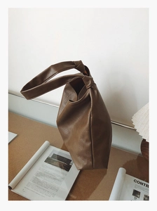 Close-up of brown vintage PU leather tote bag with unique knotted handle design