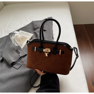 Détail rapproché du sac cabas en daim marron avec son fermoir en métal doré élégant