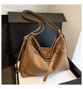 Detailed view of brown suede tote bag featuring premium gold hardware in a gift box setup