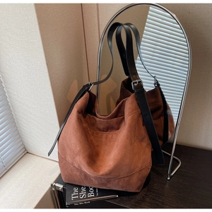 Detail of tan suede tote bag with adjustable black leather strap and silver metal buckle