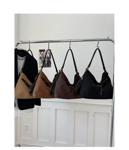 Row of vintage suede tote bags in khaki, caramel, brown, and black hanging on a metal rack